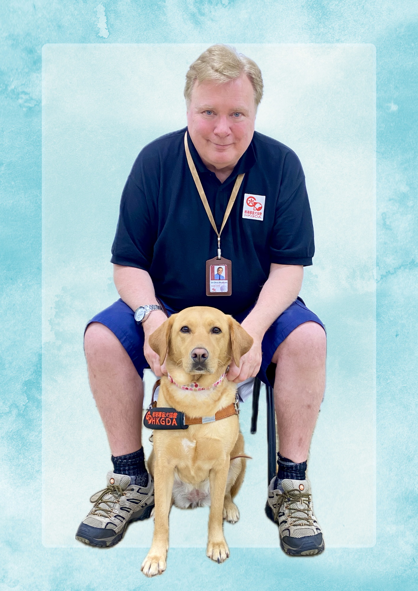 smling Chris sits behind a golden labrador